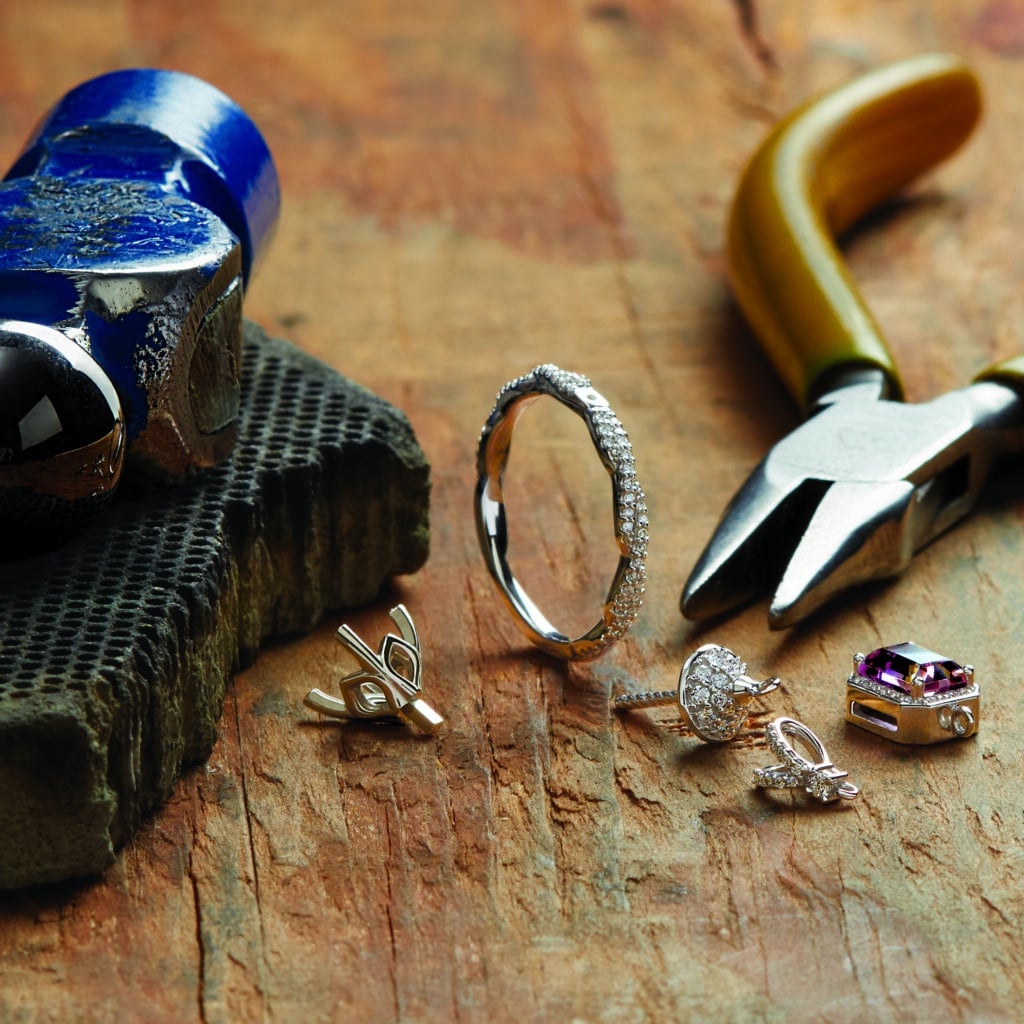 a ring and other jewelry bits sitting in between a hammer and pliers